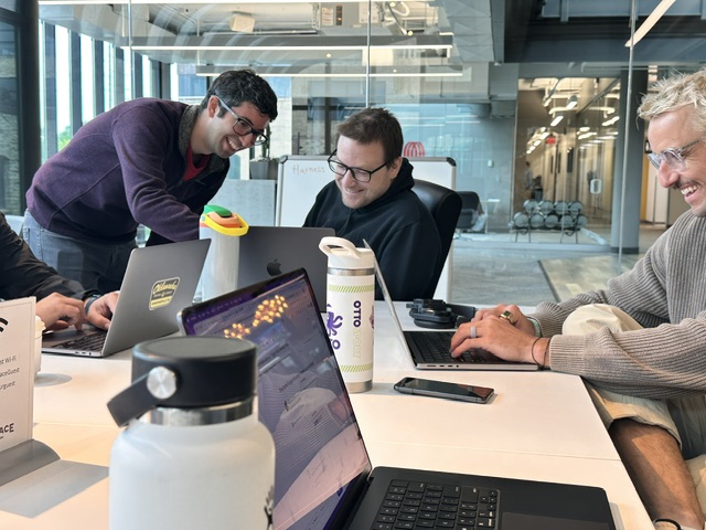 OTTO SPORT AI teammates collaborating around a laptop